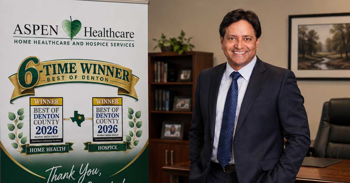 Aspen Healthcare's Sukhu George with a celebratory banner stand. It shows winners of Best of Denton for both home health and hospice.
